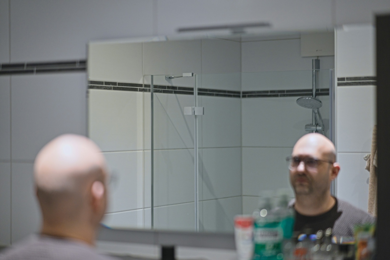 Man examining his hairline in a bathroom mirror